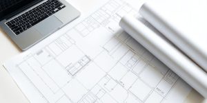 Blueprint on a desk with a laptop.